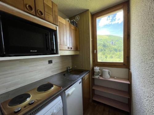 une petite cuisine avec un four micro-ondes et une fenêtre dans l'établissement Résidence Cristallin - Le Cristallin 43 - Agréable 2 pièces offrant une magnifique vue MAE-5184, à Valmorel