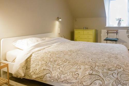 Un dormitorio con una cama blanca con una cómoda amarilla. en La maisonnette du Prince, en Brujas