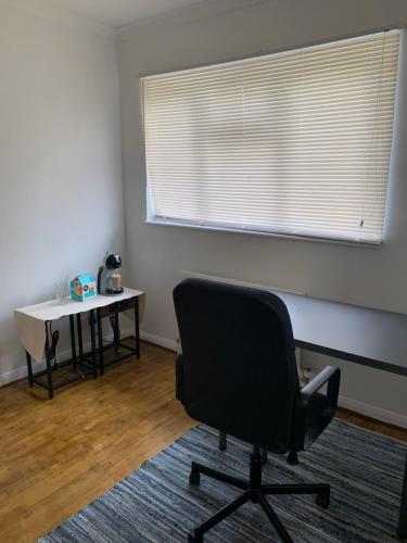 a room with a chair and a table and a window at South London Double Room in Sutton