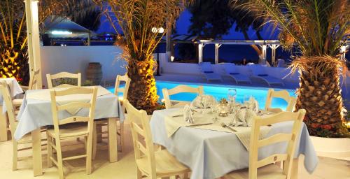 a dining room with tables and chairs and a pool at Alesahne Beach Hotel in Kamari