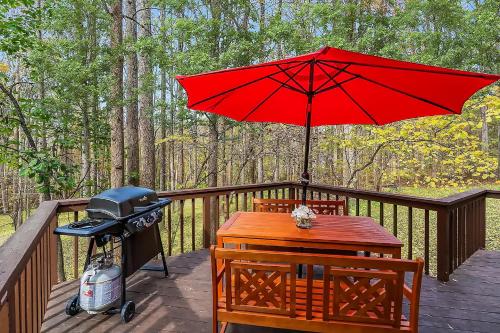 a grill and a red umbrella on a deck at Hot Tub, Deck&Grill, Game Room, WiFi at Cute Cabin in Charles Town