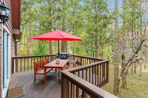 a wooden deck with a table and a red umbrella at Hot Tub, Deck&Grill, Game Room, WiFi at Cute Cabin in Charles Town