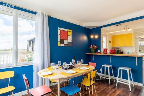une salle à manger avec des murs bleus et une table et des chaises dans l'établissement Carré Vintage, gîte années 50 avec jardin proche Laon, à Samoussy