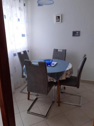 a dining room table with four chairs and a blue table and chairsktop at Apartman Lovran in Lovran