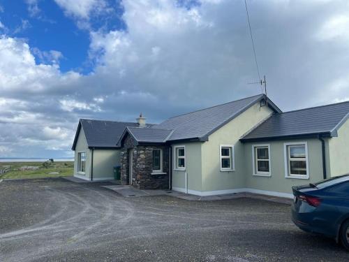 a house with a car parked in front of it at Maharees Holiday Home in Castlegregory