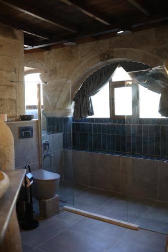 a bathroom with a toilet and blue tiles at Potamia Cave Suites in Ortahisar