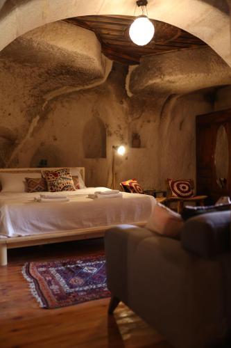 a bedroom with a bed and a couch in a room at Potamia Cave Suites in Ortahisar