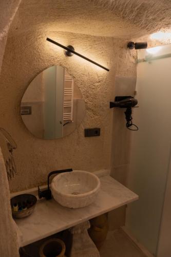 a bathroom with a stone sink and a mirror at Potamia Cave Suites in Ortahisar