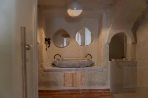 a bathroom with a tub and two mirrors on the wall at Potamia Cave Suites in Ortahisar