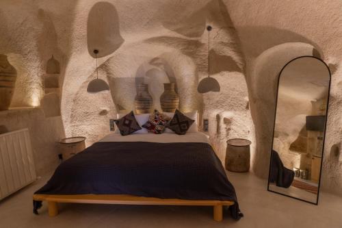 a bedroom with a bed in a stone room at Potamia Cave Suites in Ortahisar