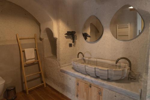 a bathroom with a tub and two mirrors on the wall at Potamia Cave Suites in Ortahisar