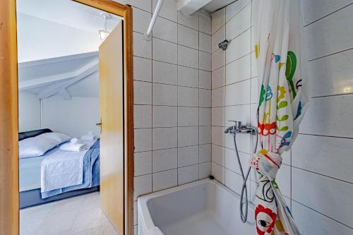 a bathroom with a bath tub and a bedroom at Olive Grove House in Ston
