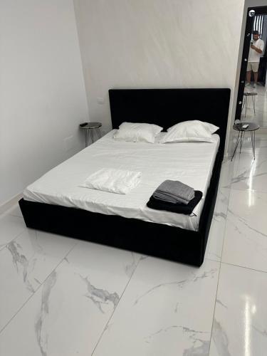 a bed with a black frame and white sheets and pillows at Garsoniera Zona Stadion in Craiova