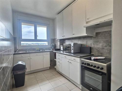 une cuisine avec des armoires blanches et un four à plaques de cuisson dans l'établissement Le dix-septième ciel vue sur la tour Eiffel, à Épinay-sur-Seine