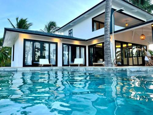 a house with a swimming pool in front of a house at Vila Laguna Beach, kitesurf na Ilha do Guajiru in Itarema