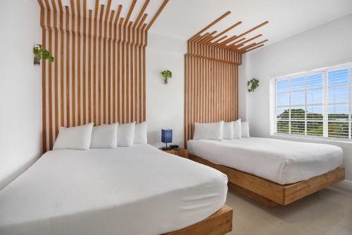 a bedroom with two beds and a window at Hotel Belleza in Miami Beach