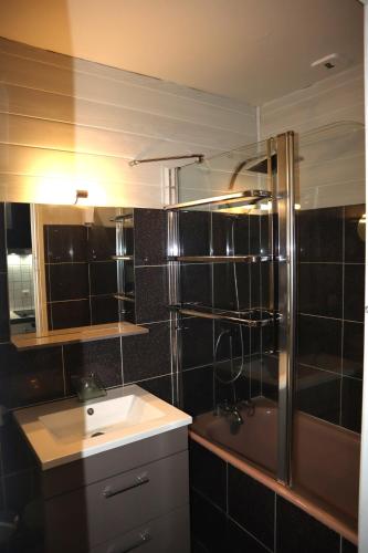 une salle de bain avec un lavabo et une douche dans l'établissement 201, Les Ambassadeurs, à La Bourboule