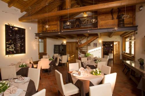 a restaurant with white tables and white chairs and wooden ceilings at La Burla in Borgosesia