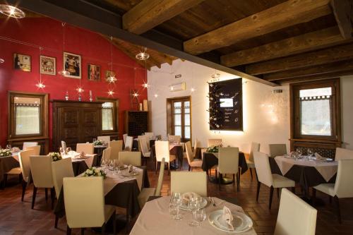 a restaurant with white tables and chairs and red walls at La Burla in Borgosesia