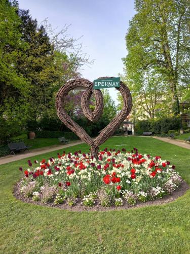 a heart statue in a bed of flowers in a park at Les Loges Du Théatre 160m2 PRIVÉ 14 personnes MAX tout équipé a 200m de l'AVENUE DE CHAMPAGNE et toutes commodités DEGUSTATION CHAMPAGNE OFFERTE jacuzzi sauna jeux velos EMPLACEMENT EXCEPTIONNEL et CHIC in Épernay