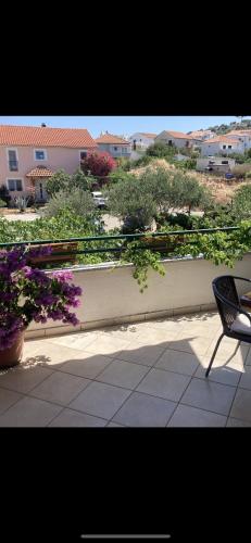 ein Balkon mit einem Stuhl und Blumen auf einer Terrasse in der Unterkunft Giovani in Murter