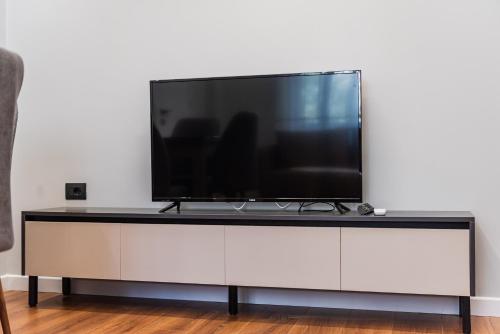 a flat screen tv sitting on top of a white cabinet at SR Apartments Golem in Golem