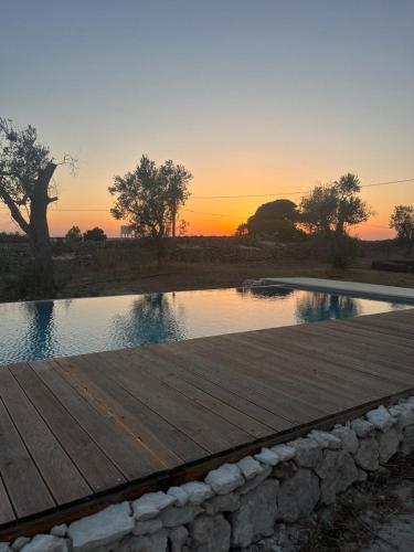 a pool of water with a sunset in the background at Terecate Experimental Relais in Melendugno