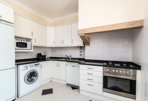 a kitchen with white cabinets and a washer and dryer at Varanda dos Poetas in Lisbon