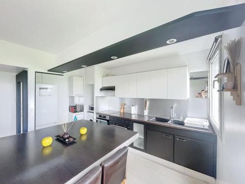 une grande cuisine avec un grand comptoir noir dans l'établissement Grand appartement neuf entre Paris et Disneyland, à Noisy-le-Grand