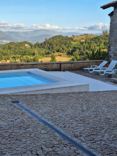 a swimming pool with two lounge chairs next to a house at Casa da Anta Grande in Celorico de Basto