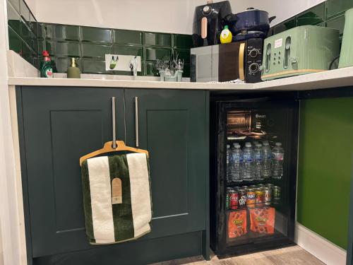 a kitchen with green cabinets and a sink with a towel at Southgate Luxury Apartments-Jaquzzi Bath-Private Parking- 2 Min M62 in Elland