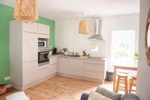 une cuisine avec des armoires blanches et un four à plaques de cuisson dans l'établissement Immeuble de 3 appartements avec cour intérieure, à Brest