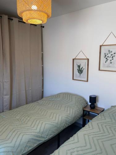 une chambre avec deux lits et un lustre dans l'établissement Charmant Appart clim 6 pers, Sorgues Vaucluse 2, à Sorgues