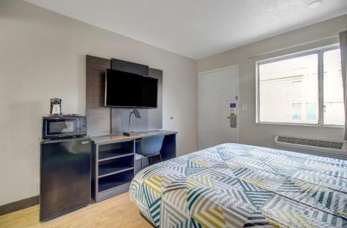 a bedroom with a bed and a desk with a television at Motel 6-Venice, FL in Venice