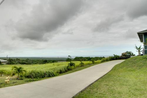 a road leading up to a house on a grassy hill at The Aloha Green House Retreat with Ocean Views! in Naalehu
