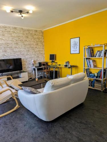 - un salon avec un canapé blanc et un mur jaune dans l'établissement L'Horizon Spacieux - Parking Gratuit, à Mâcon