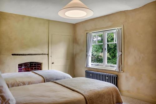 a bedroom with two beds and a window at Gorgeous English Farmhouse Holiday Cottage for 9 and a half in Ellingham