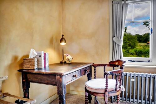 an old wooden desk with a chair and a window at Gorgeous English Farmhouse Holiday Cottage for 9 and a half in Ellingham