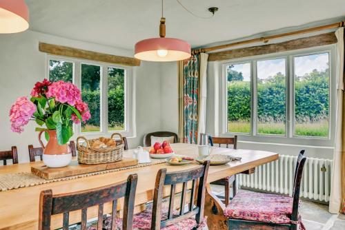 a dining room with a table and chairs and windows at Gorgeous English Farmhouse Holiday Cottage for 9 and a half in Ellingham