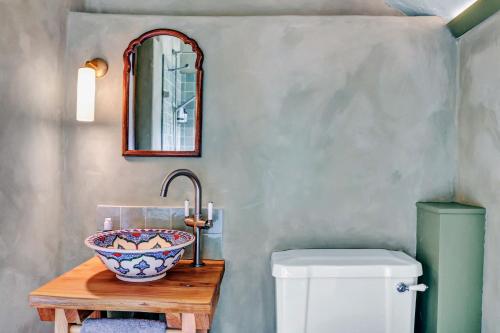 a bathroom with a bowl on a table next to a toilet at Gorgeous English Farmhouse Holiday Cottage for 9 and a half in Ellingham