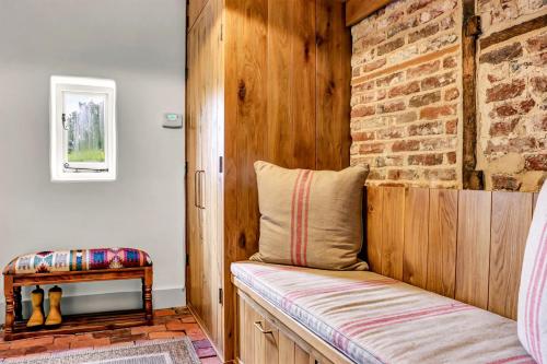 a bench in a room with a brick wall at Gorgeous English Farmhouse Holiday Cottage for 9 and a half in Ellingham