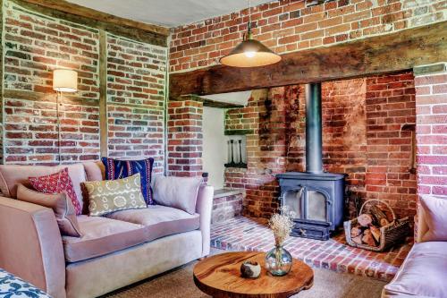 a living room with a couch and a brick fireplace at Gorgeous English Farmhouse Holiday Cottage for 9 and a half in Ellingham