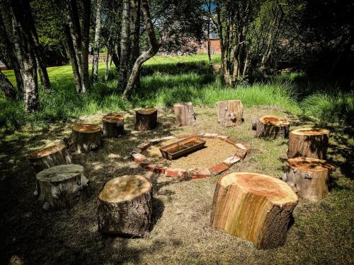a group of logs and a fire pit in a yard at Gorgeous English Farmhouse Holiday Cottage for 9 and a half in Ellingham