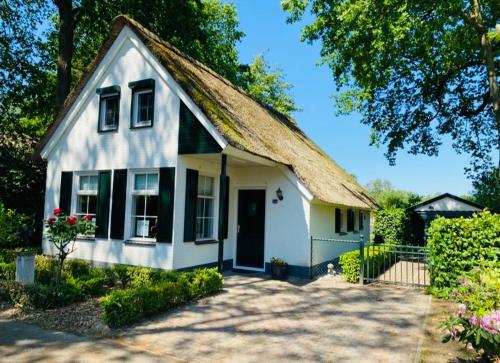 a small white house with a thatched roof at Vakantiehuis Villa 56 in Heel