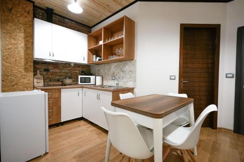 een keuken met een houten tafel en witte stoelen bij Ora Apartment in Gjirokastër
