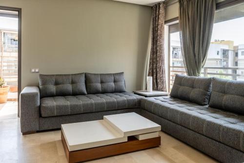 a living room with a couch and a table at Sublime duplex, piscine, parking in Bouskoura