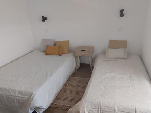 zwei Einzelbetten in einem Zimmer mit Nachttisch und Bettvolant in der Unterkunft Casa da Tia Avelina in Angra do Heroísmo