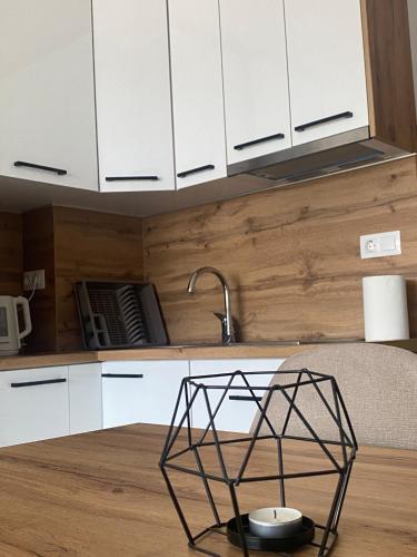 a kitchen with white cabinets and a bowl on a table at Apartman Green in Šišava