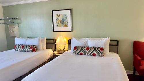 a hotel room with two beds and a red chair at Marina Village Inn in Alameda