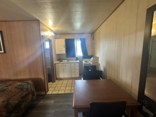 a small room with a table and a kitchen at Pine Ridge Motel in Timmins
